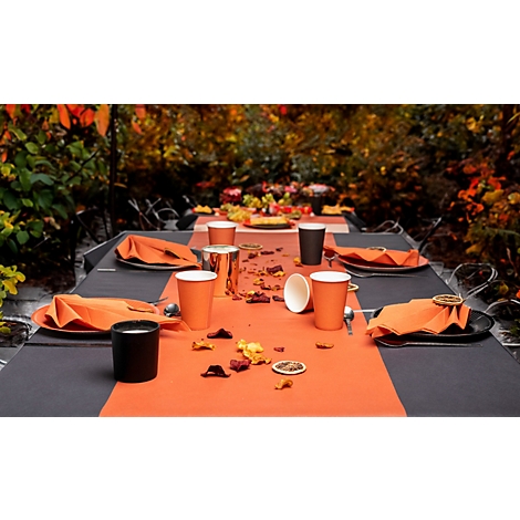 Table d'automne festive : serviettes, gobelets et chemin de table orange, décorés de fleurs et de fruits.