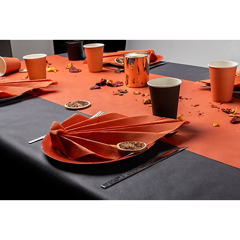 Table dressée de façon festive avec des serviettes orange, des tasses et des décorations.