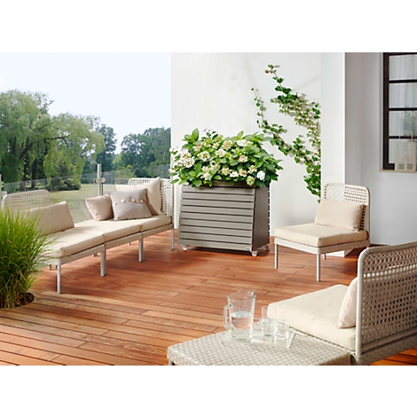 Terras met houten vloer, tuinmeubelen, bloembak en planten op de achtergrond. Een uitnodigende scène.