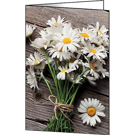 Close-up of a bouquet of white daisies with yellow centers, on a wooden background. One flower lies next to it.