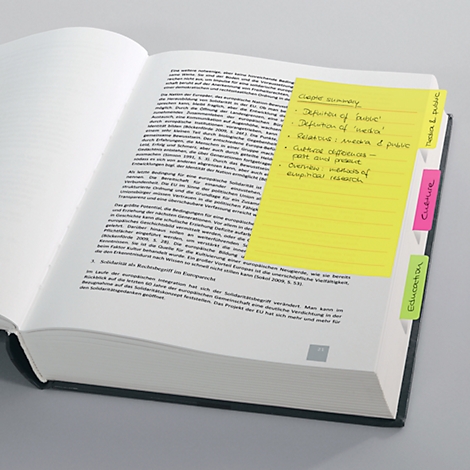 Ein offenes Buch mit gelbem Haftzettel und Text. Mehrere farbige Register am Rand.