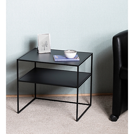 Table d'appoint noire à deux niveaux. Sur le niveau supérieur, il y a un bol, un livre et un cadre photo.