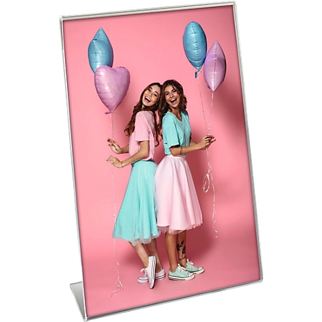 Deux jeunes femmes, bras dessus bras dessous, sourient et posent devant un fond rose décoré de ballons.