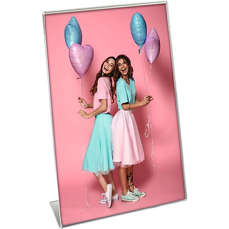 Zwei junge Frauen, Arm in Arm, lächeln und halten Ballons vor rosa Hintergrund.