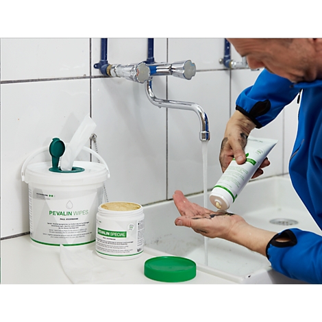 A man washes his hands with soap under running water. Cleaning utensils are in the background.