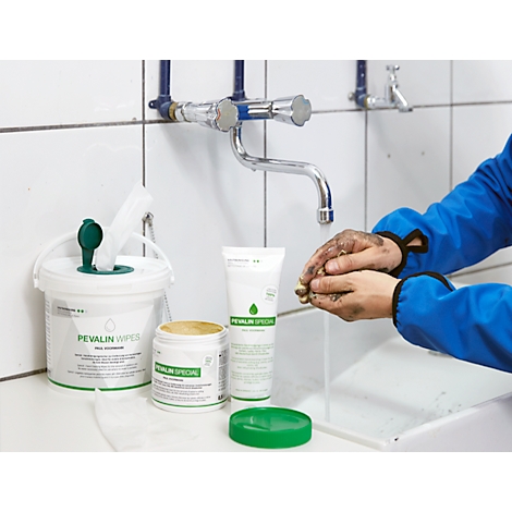 Person washing dirty hands under a faucet. Cleaning products to the left. Blue work clothes.