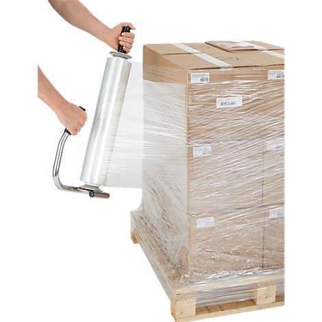 Hände nutzen einen Abroller, um eine Palette mit Kartons in transparente Stretchfolie einzuwickeln.