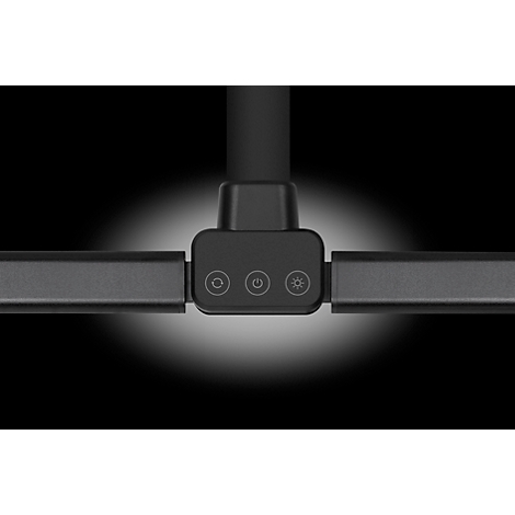 Nahaufnahme einer schwarzen Schreibtischleuchte mit drei Knöpfen und Licht-Symbol. Schwarzer Hintergrund, beleuchtet.