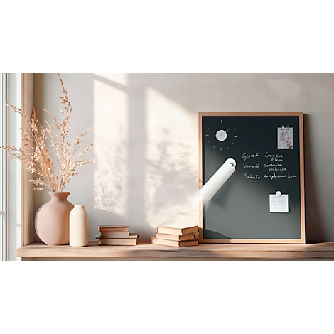 Zwart bord met notities, een lichtbundel en decoratie op een houten plank. Naast het bord staan een vaas en boeken.
