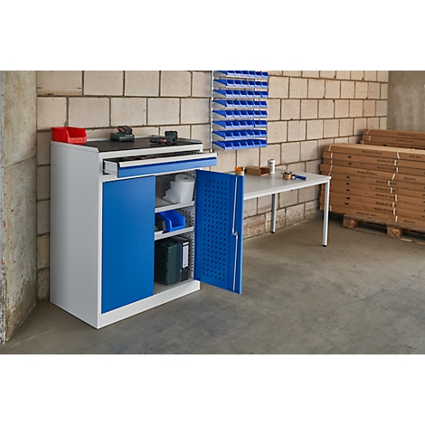 Workshop cabinet in workshop, turquoise blue door, white work surface, blue storage bins on wall.