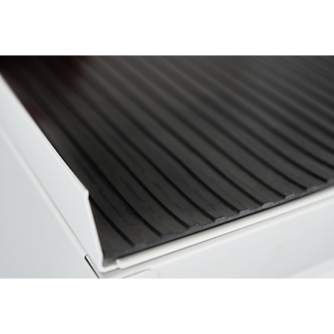 Close-up of a black, grooved surface resting on a white structure.