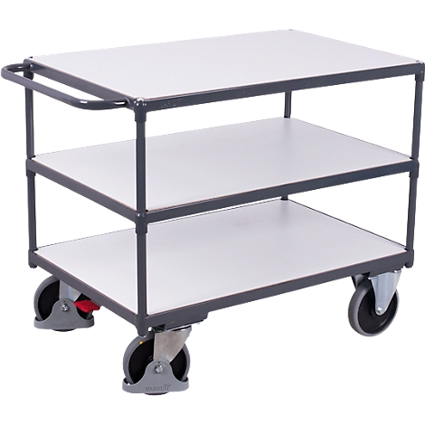 A grey serving cart with three white shelves and four wheels. It has a handle for pushing.
