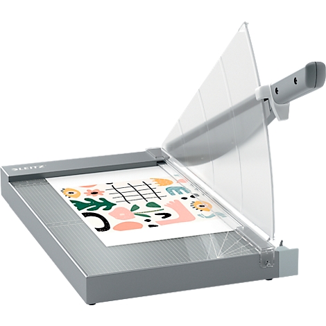 Grauer Papierschneider, mit transparentem Schutz. Auf dem Papier ein farbenfrohes Muster.