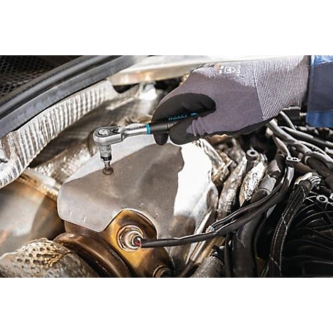 Een persoon met handschoenen schroeft met gereedschap aan een motor. Onderdelen van de motor zijn in detail zichtbaar.