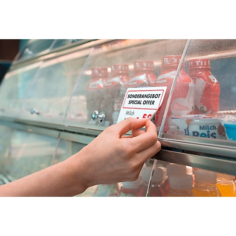 Eine Hand greift nach einem Sonderangebotsschild vor Getränken in einem Kühlschrank. Auf dem Schild steht 'Sonderangebot/Special Offer'.