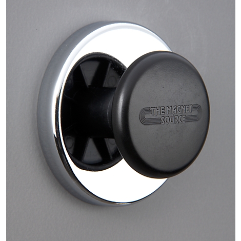 Black magnet with "THE MAGNET SOURCE" on a silver ring on a grey wall.