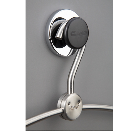 Chrome towel holder, mounted on grey wall. Black knob with lettering. Below the bracket a towel ring.