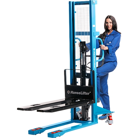 A woman stands next to a blue forklift and holds onto the handle.