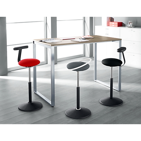 Three ergonomic stools in front of a desk. One is red, the others are black.