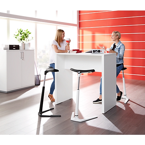 Two women are conversing at a white high table. They sit on height-adjustable stools in a modern office.