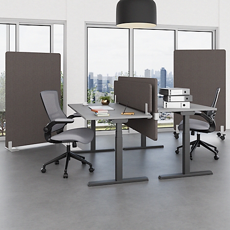 Büro mit grauen Schreibtischen, Trennwänden und Bürostühlen vor Fensterfront. Im Hintergrund eine Stadt.
