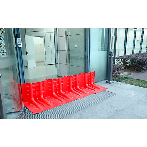 Rote Flutschutzbarriere vor einer Glastür. Schutz vor Überflutung in Gebäuden. Im Hintergrund ein Flur.