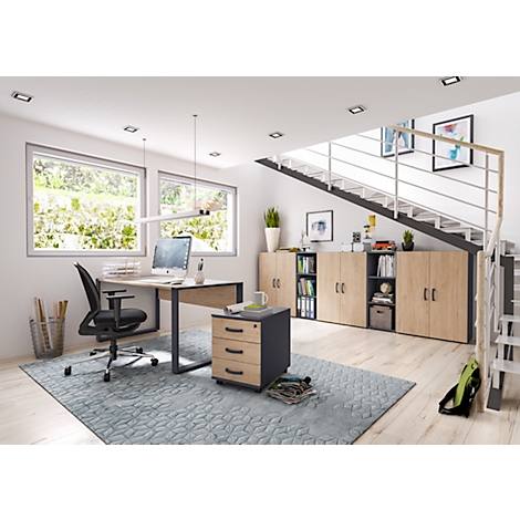 Office with desk, chair, mobile pedestal, cabinet wall and staircase. Bright ambience with daylight and plants.