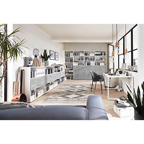A modern office with desk, bookshelves, and plants. The room is bright and welcoming.