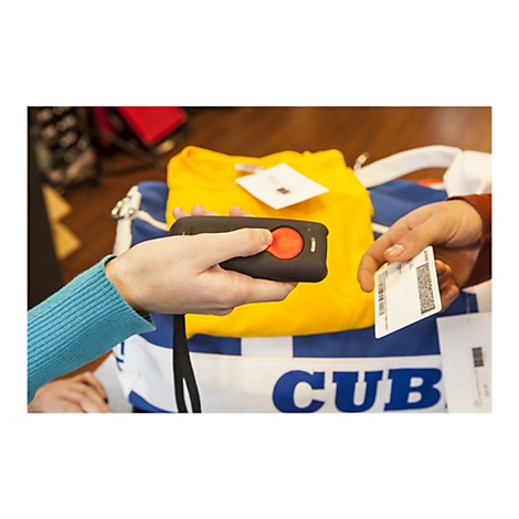 Hände halten einen Barcode-Scanner und eine Karte. Auf einem gelben T-Shirt hängt ein Preisschild. Im Hintergrund eine blaue Tasche mit weißer Aufschrift.