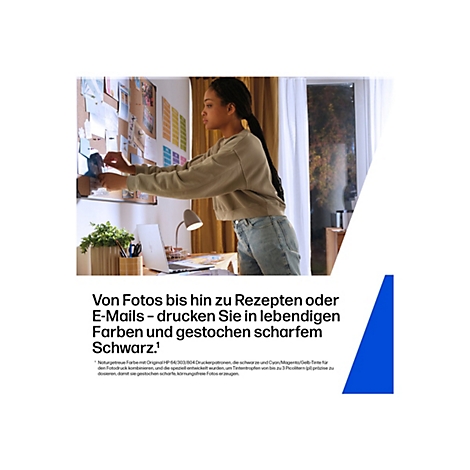 Eine Frau befestigt Fotos an einer Pinnwand. Auf einem Schreibtisch stehen ein Laptop, eine Schreibtischlampe und Pflanzen.
