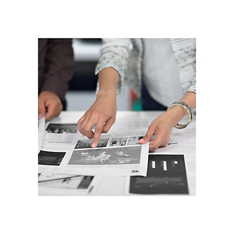 Deux personnes examinent ensemble des impressions avec des graphiques et des cartes. Une main pointe vers une image.