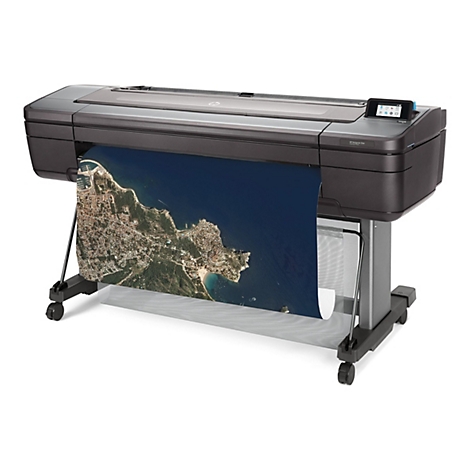 Grand traceur imprimant une vue aérienne, montrant une ville avec une côte et la mer. Traceur est gris, support noir, fond blanc.