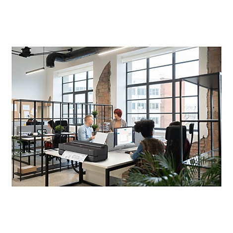 Ein Büro mit Menschen, die an Schreibtischen arbeiten. Ein grosser Drucker druckt einen Plan. Im Hintergrund Fenster mit Ausblick.