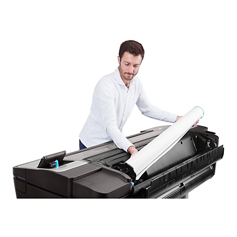 Ein Mann in weißem Hemd legt eine Papierrolle in einen großen Drucker ein.