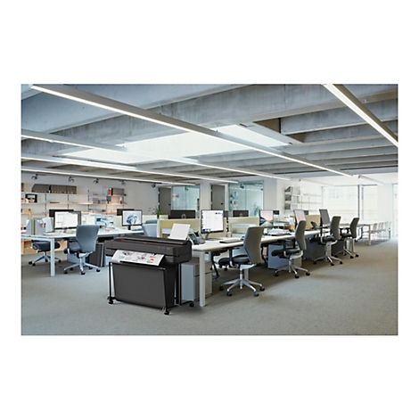 Büro mit mehreren Schreibtischen, Computern und einem großen Drucker; auf einem Blatt Papier ist ein Diagramm dargestellt.