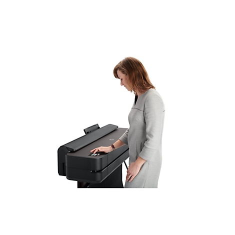 Eine Frau in grauer Kleidung bedient einen schwarzen Drucker. Sie drückt einen Knopf und blickt auf das Gerät.