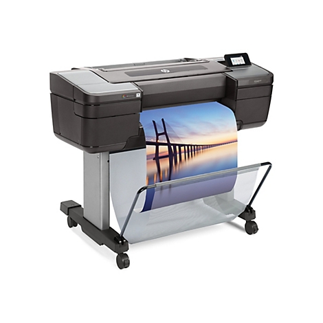 Großer, schwarzer HP-Plotter mit Papierausdruck: Brücke am Meer bei Sonnenuntergang. Der Plotter steht auf Rollen.