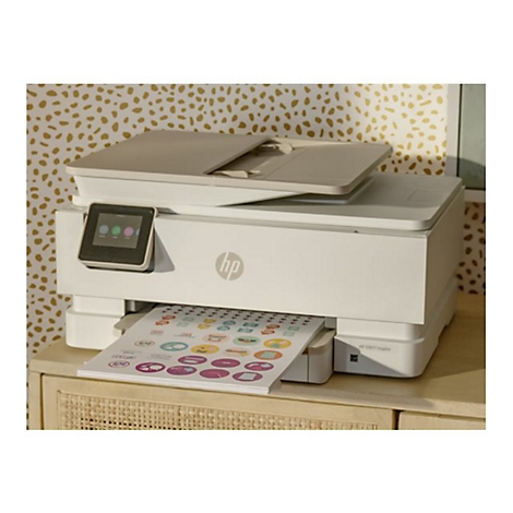 Weißer HP-Drucker mit ausgedruckten Aufklebern. Der Drucker steht auf einem cremefarbenen Tisch vor einer Wand mit goldenen Punkten.