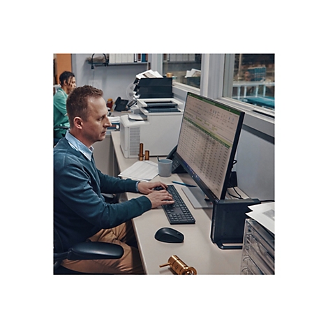 Ein Mann sitzt an einem Schreibtisch, tippt auf einer Tastatur und schaut auf einen Computerbildschirm. Auf dem Schreibtisch liegen ein Stift, eine Maus und Metallteile.