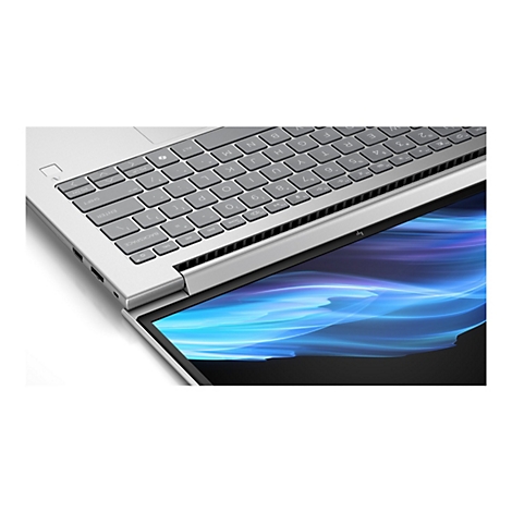 Nahaufnahme eines silberfarbenen Laptops, der teilweise geöffnet ist. Die Tastatur und ein Teil des Bildschirms sind sichtbar. Auf dem Bildschirm sind blaue Lichteffekte zu sehen.