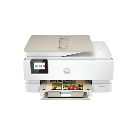 Ein weißer HP ENVY Inspire Drucker mit beige Deckel und Papiereinzug, auf dem Bilder gedruckt werden. Auf dem Display ist die Uhrzeit zu sehen.