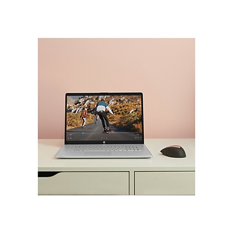 Ein Laptop mit einem Video von Skateboardern, daneben eine Maus. Auf einem cremefarbenen Tisch vor einem rosa Hintergrund.