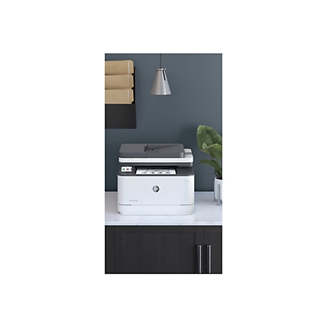 Ein weißer HP-Laserdrucker steht auf einer Marmorarbeitsplatte. Der Hintergrund ist ein dunkles Blau, es hängen Ordner und eine Lampe an der Wand.