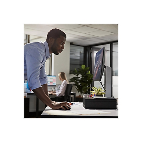 Ein Mann im BÃ¼ro, der auf einen Monitor blickt. Im Hintergrund arbeitet eine weitere Person.