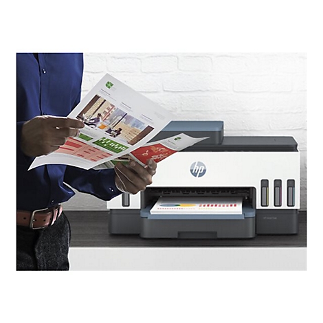 Une personne tient des documents dans ses mains, devant une imprimante HP. Le papier est imprimé par l'imprimante.