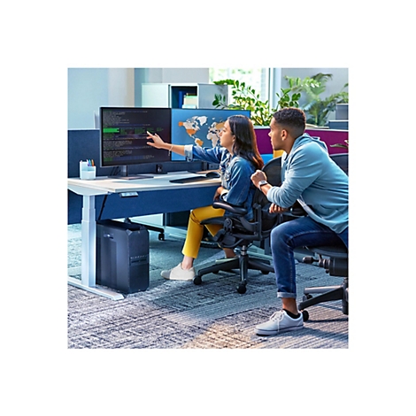 Zwei Personen sitzen an einem Schreibtisch, der an einem Computer arbeitet. Eine Person zeigt auf den Bildschirm, der Code anzeigt. Die andere Person schaut zu.