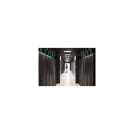 Ein Mann steht in einem Serverraum zwischen Reihen von schwarzen Serverracks. Kabel verlaufen an der Decke.