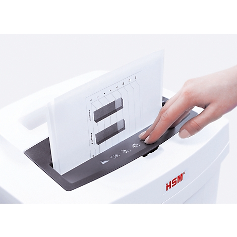 Hand presses button on shredder. A sheet with a diagram is being shredded. Logo: HSM.