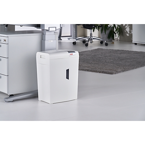 White paper shredder in an office setting. Gray rug on the right, white desk on the left.