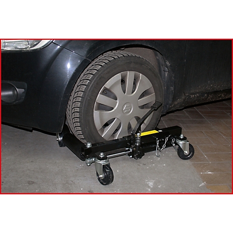 Schwarzes Auto, dessen Reifen auf einem Wagenheber mit Rollen steht. Die Felge trägt das Suzuki-Logo.